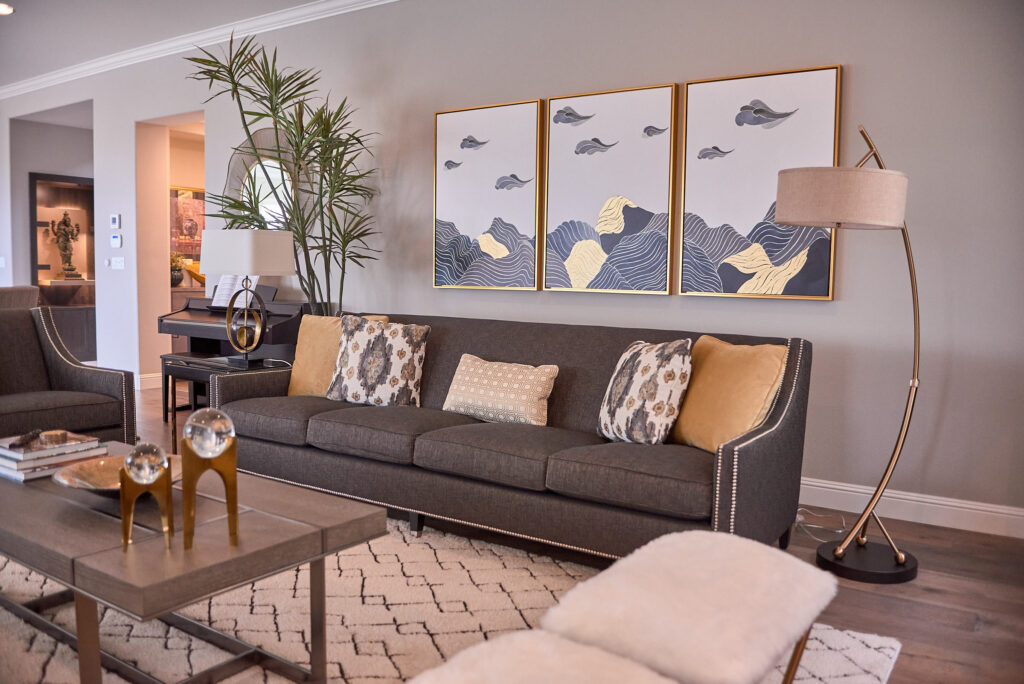 raashi-design-pleasanton-ca-repetition-with-motifs-in-design-living-room-with-blue-sofa-framed-art-above-dark-coffee-table-curved-lamp-elegant-interior-design